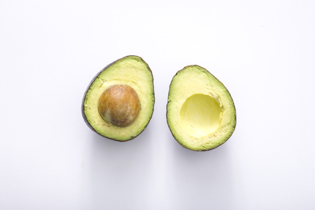 A ripe avocado cut in half showing creamy green flesh and the pit