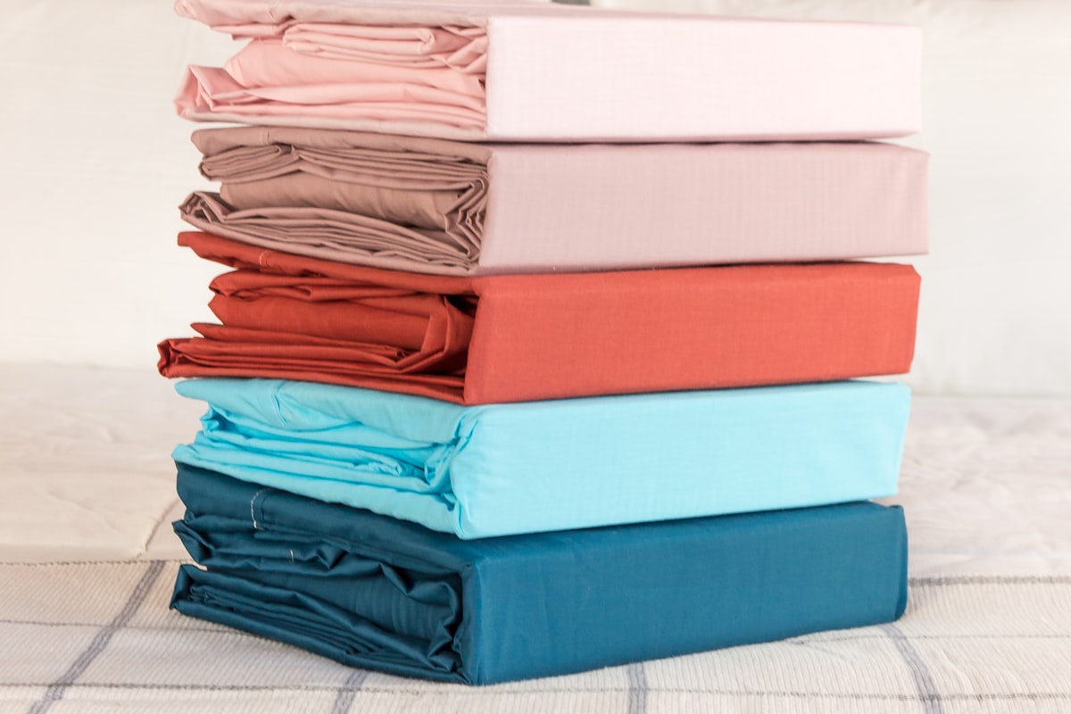 A neat stack of folded bed sheets in different colors