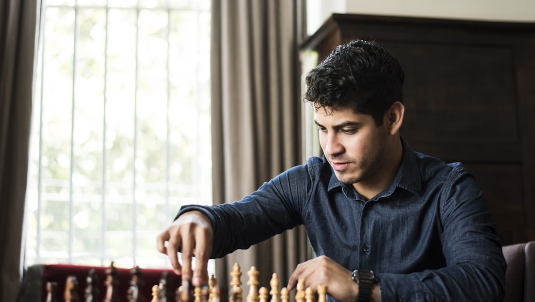 Man in a blue shirt concentrating over a chess board