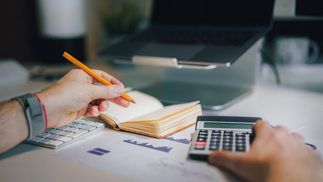 Person at a desk with a calculator and an open notebook