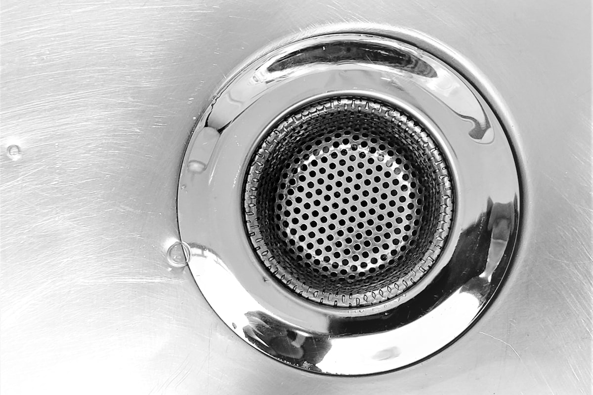 Close-up of a stainless steel kitchen sink drain and strainer