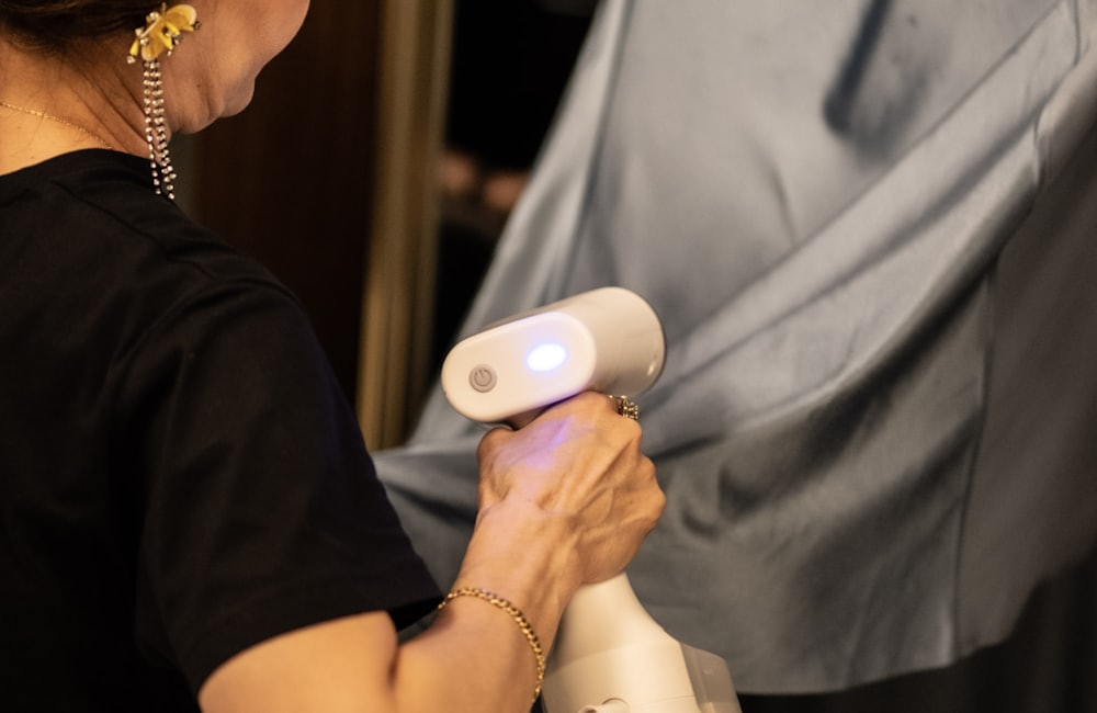 A person steaming a grey garment with a handheld steamer