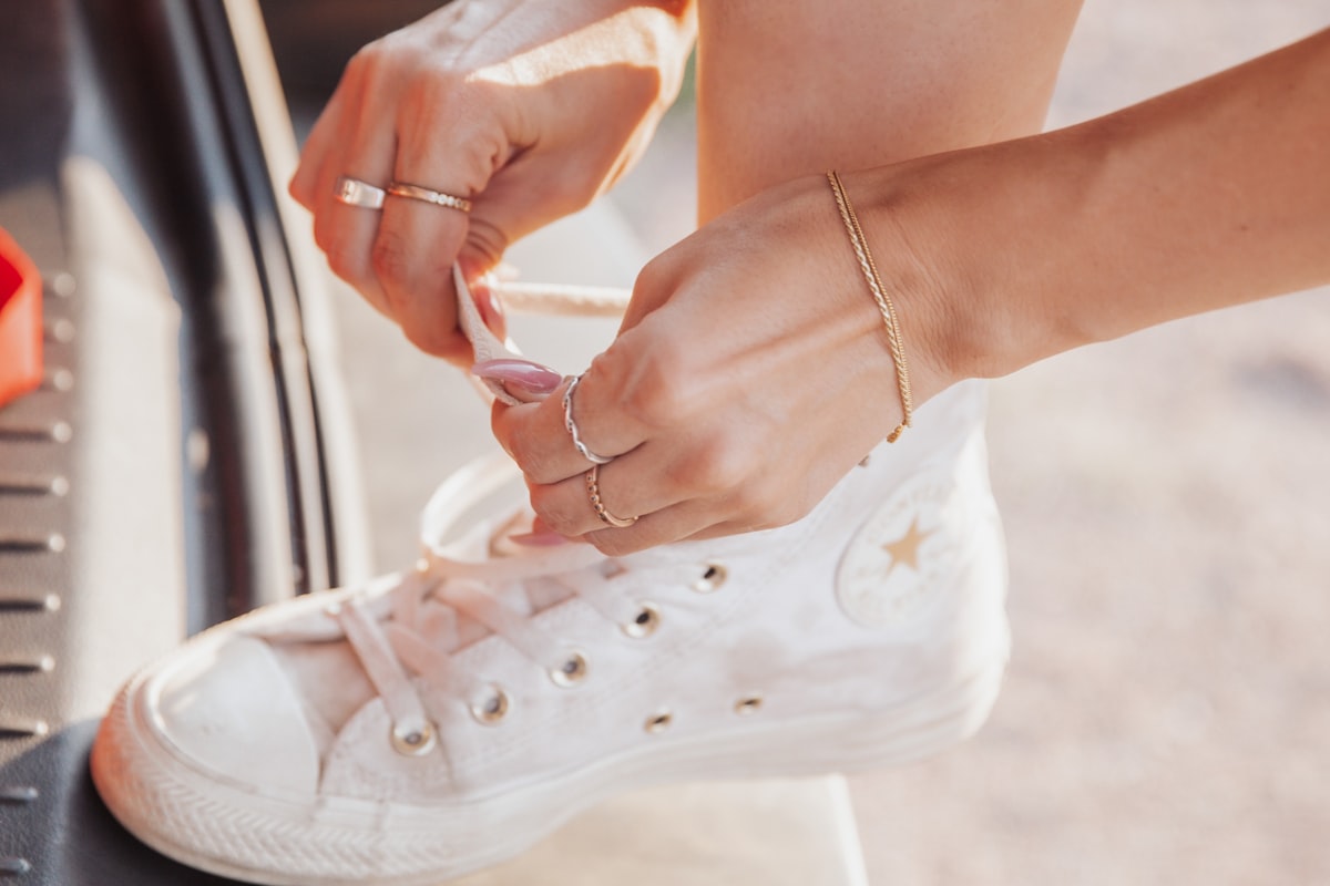 Person lacing up a pair of white canvas sneakers