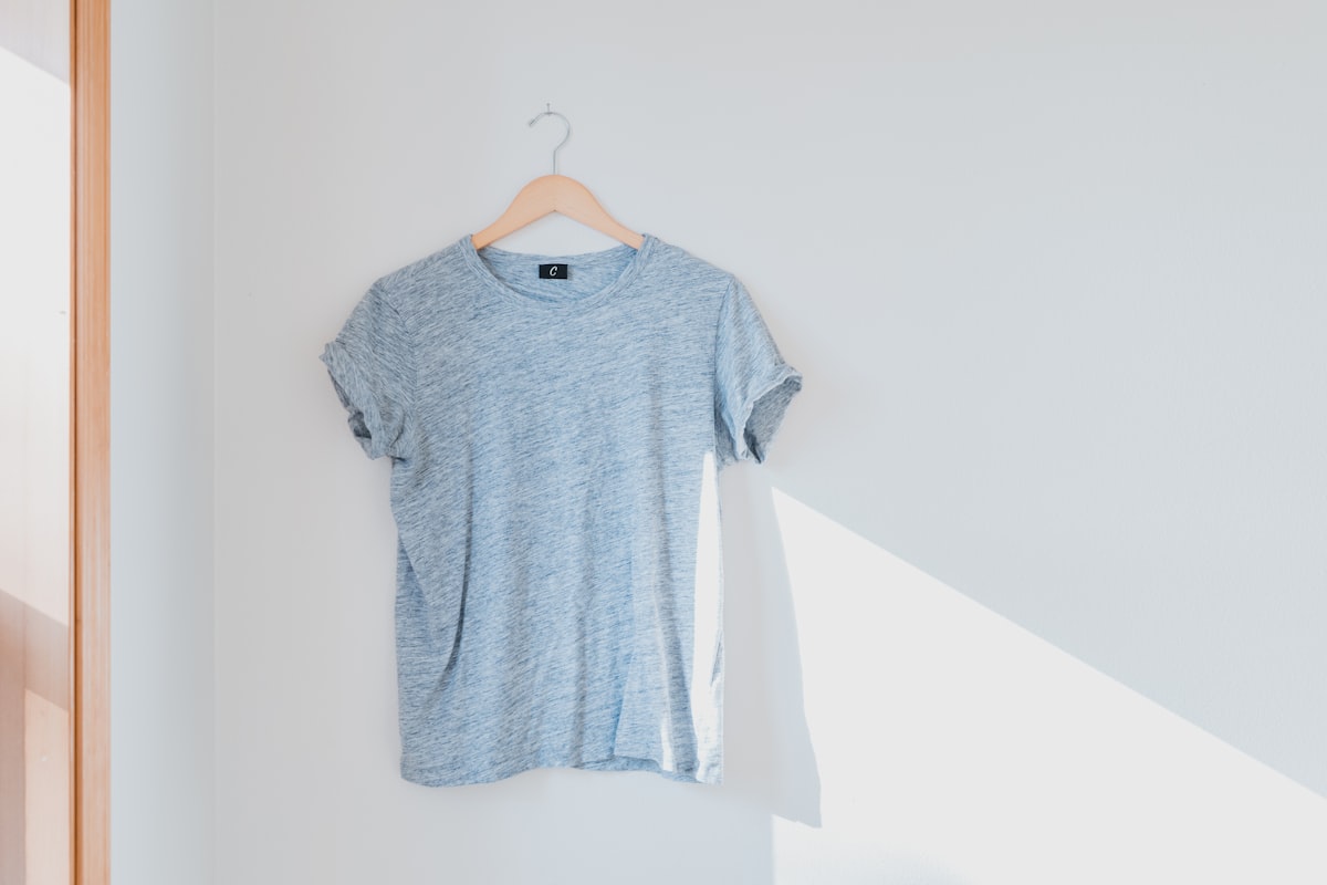 A grey shirt hanging on a white wall